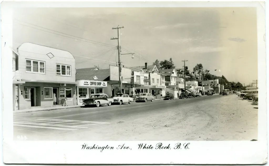 A postcard view of shops and parked cars along Washington Avenue, White Rock.